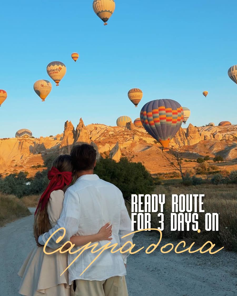 A couple watching hot air balloons rise over Cappadocia at sunrise