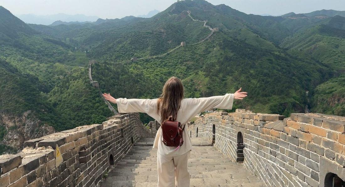 On the Great Wall of China with arms outstretched