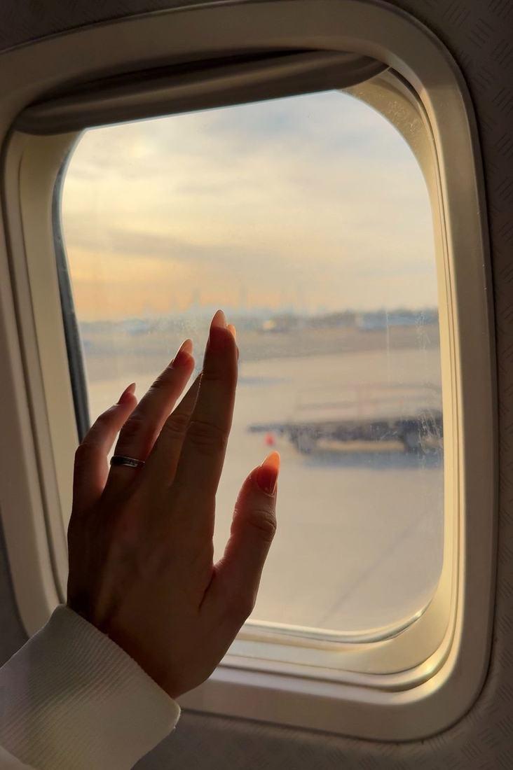 A hand against the cabin window of a plane bound for Beijing