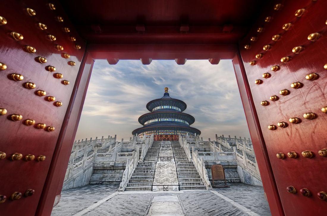 The blue-roofed round pavilion of the Temple of Heaven framed by a red studded gate