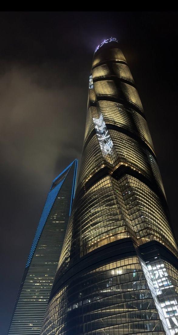 Shanghai Tower lit up against the night sky
