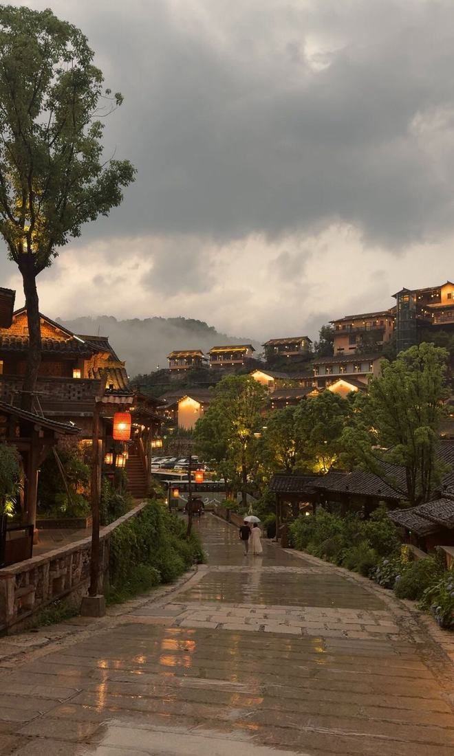 Lanterns glowing over a hillside town at dusk